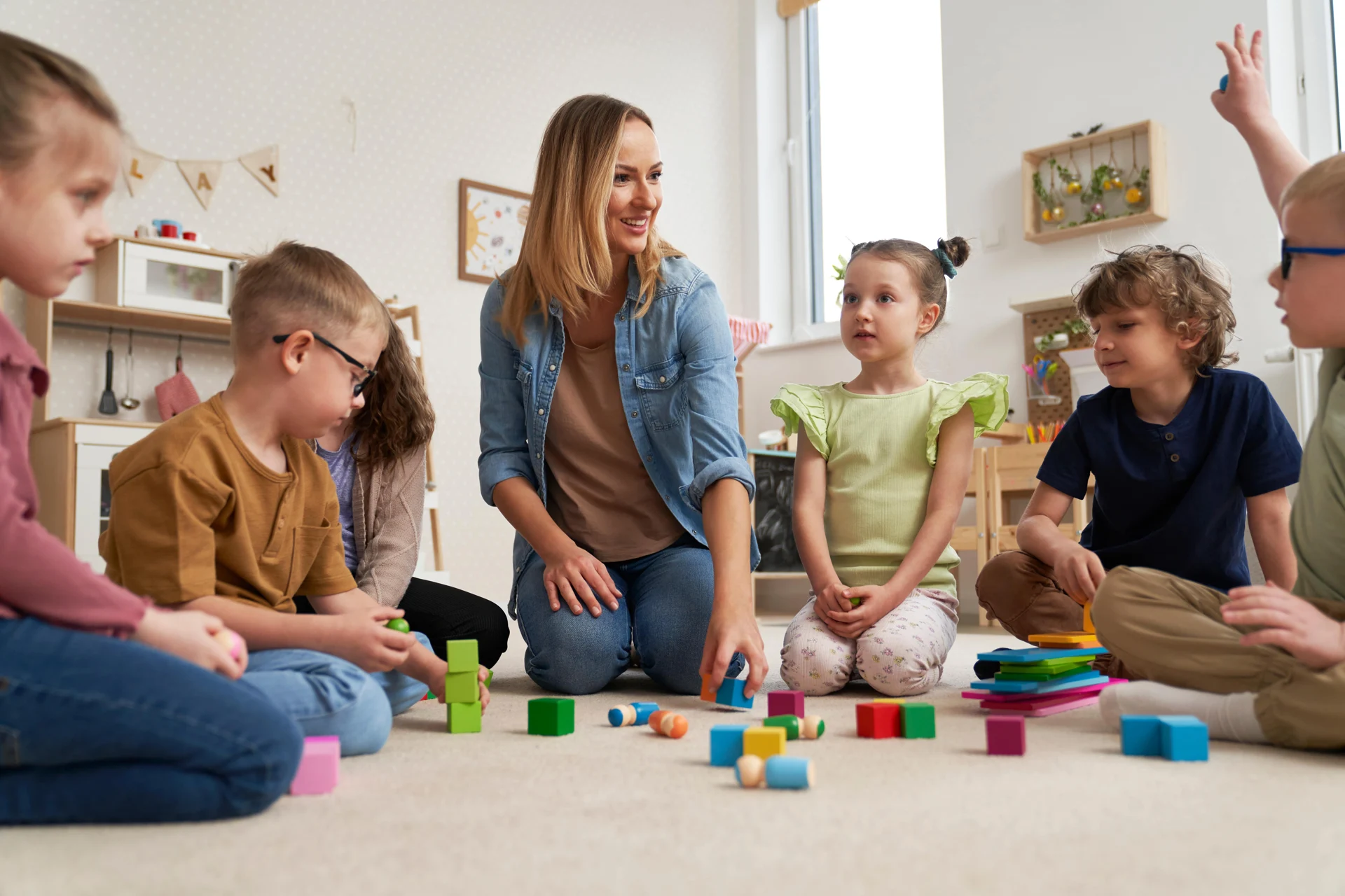 A teacher and young children exploring colorful building blocks together